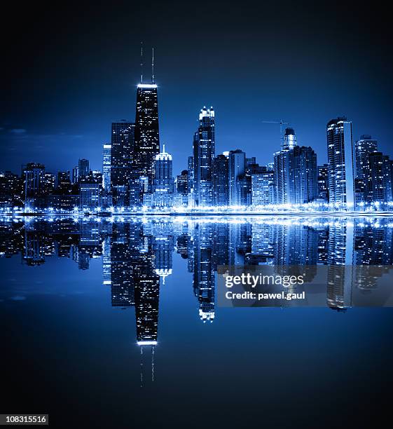 A stunning city skyline at night with illuminated buildings and reflections in the water